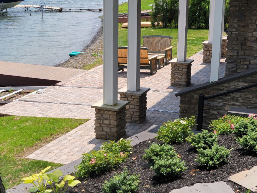 Lakeside paver patio walkway with seating area under a covered structure, leading toward the water and dock in Seneca Falls, NY.